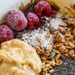 Delicious breakfast bowl with fresh raspberries, granola, and nut butter for a healthy start.
