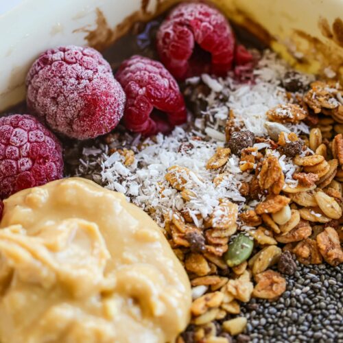 Delicious breakfast bowl with fresh raspberries, granola, and nut butter for a healthy start.